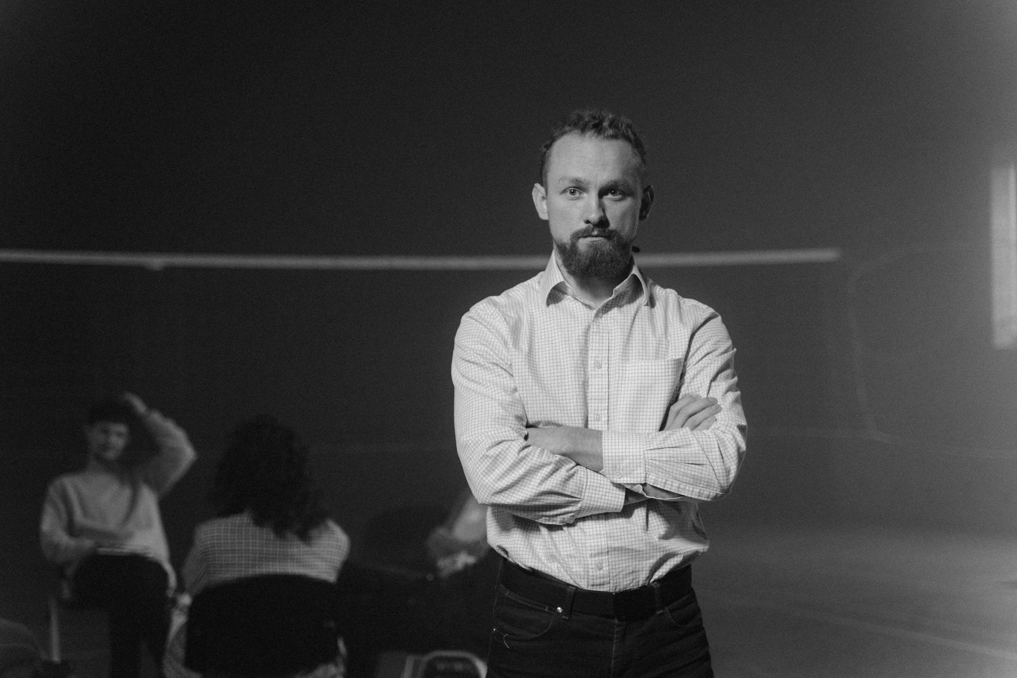 Monochrome photo of a group therapy session with a man standing in focus.